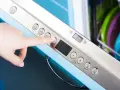 Dłoń naciska przycisk "eco" na panelu zmywarki Electrolux, przygotowując ją do ekologicznego cyklu czyszczenia.