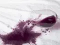 Rozlane czerwone wino na białym materiale. Dowiedz się, jak usunąć plamę z wina, zanim zaschnie.