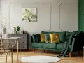 Jak rozjaśnić salon z ciemnymi meblami? Zielona sofa, złote akcenty i jasne dodatki dodają lekkości.