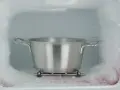 Metalowy garnek z wodą stoi na kratce w zamrażarce, czekając na rozmrażanie lodówki. Wokół śnieg i lód.