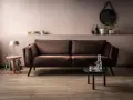 Elegancki brązowy narożnik w salonie, idealnie komponuje się z pastelowymi ścianami i drewnianą podłogą.