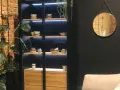 Elegancka witryna w salonie z podświetlanymi półkami, na których stoją misy i filiżanki. Idealna inspiracja, co wstawić do witryny w salonie.