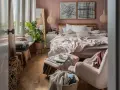 Przytulna sypialnia inspiracje: łóżko z różową pościelą, wiklinowe lampy, dużo roślin i miękkie koce tworzą ciepłą atmosferę.