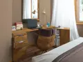 Stylowe biurko w sypialni aranżacje: drewniany blat, wygodny fotel, laptop i lampka tworzą funkcjonalne miejsce do pracy.