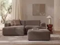 Wygodna sofa i puf w kolorze greige jaki to kolor, idealnie komponują się z jasnym wnętrzem i widokiem na drzewa.