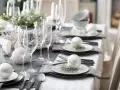 Elegancko nakryty stół na Boże Narodzenie: białe bombki, gałązki jodły, kieliszki i szare serwetki. Inspiracja, jak udekorować stół na Boże Narodzenie.