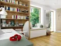 Przytulna biblioteczka w salonie z pluszakami, książkami i wygodnym miejscem do siedzenia przy oknie.