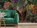 Aksamitna sofa w odcieniach zieleni, obok niej drewniane stoliki z bukietem. W tle bujna, tropikalna tapeta z kwiatami i liśćmi.