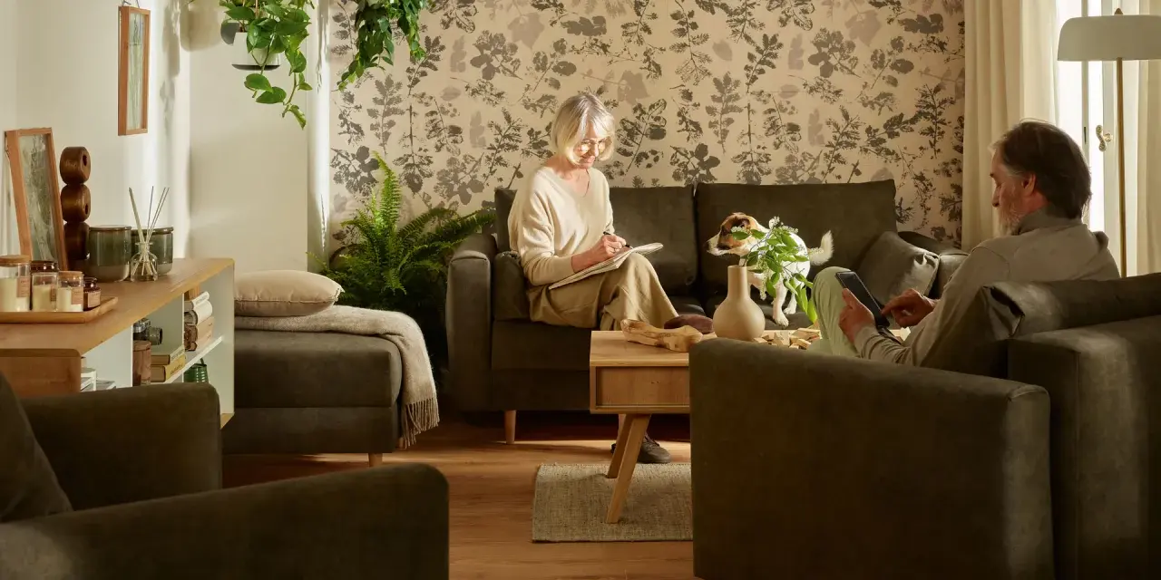 Przytulny salon, gdzie starsza pani pisze w notatniku, a pan czyta na tablecie. Idealne miejsce, by pomyśleć, jak urządzić pokój dla babci.