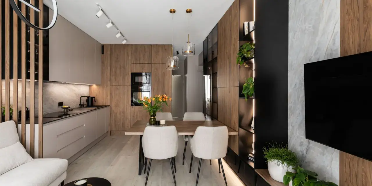 Nowoczesny salon z kuchnią i jadalnią 40m2. Drewniane akcenty, jasne meble i rośliny tworzą przytulną atmosferę.