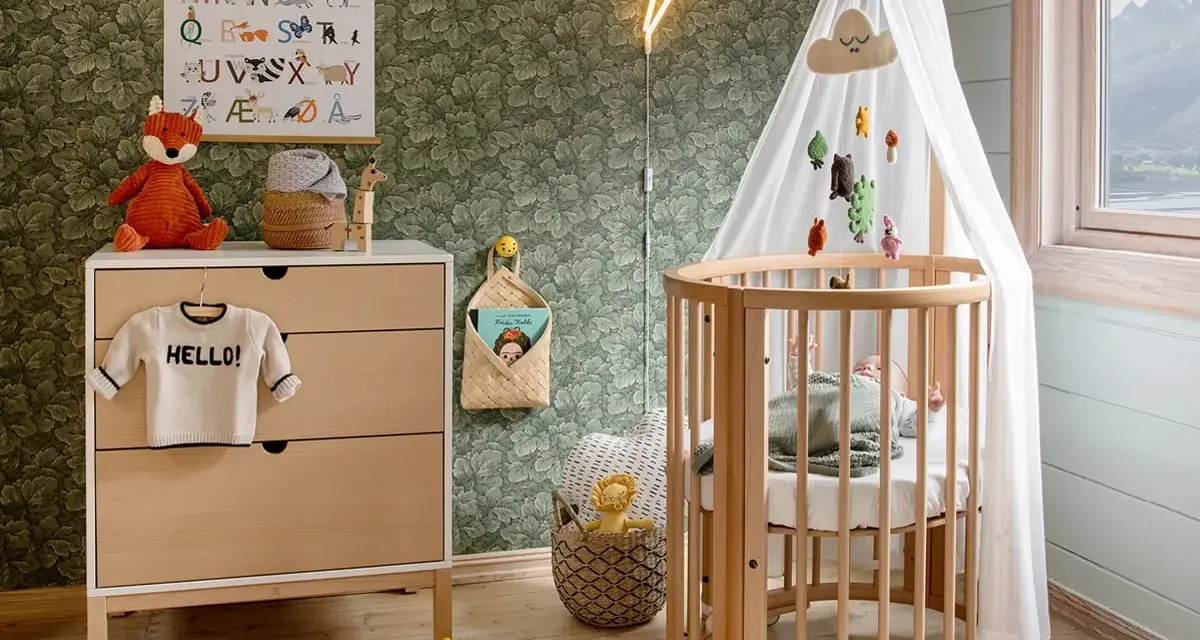 Uroczy kącik dla noworodka w sypialni: drewniane łóżeczko z baldachimem, komoda z zabawkami i ubrankiem "HELLO!", plakat z literkami i neonowa błyskawica.