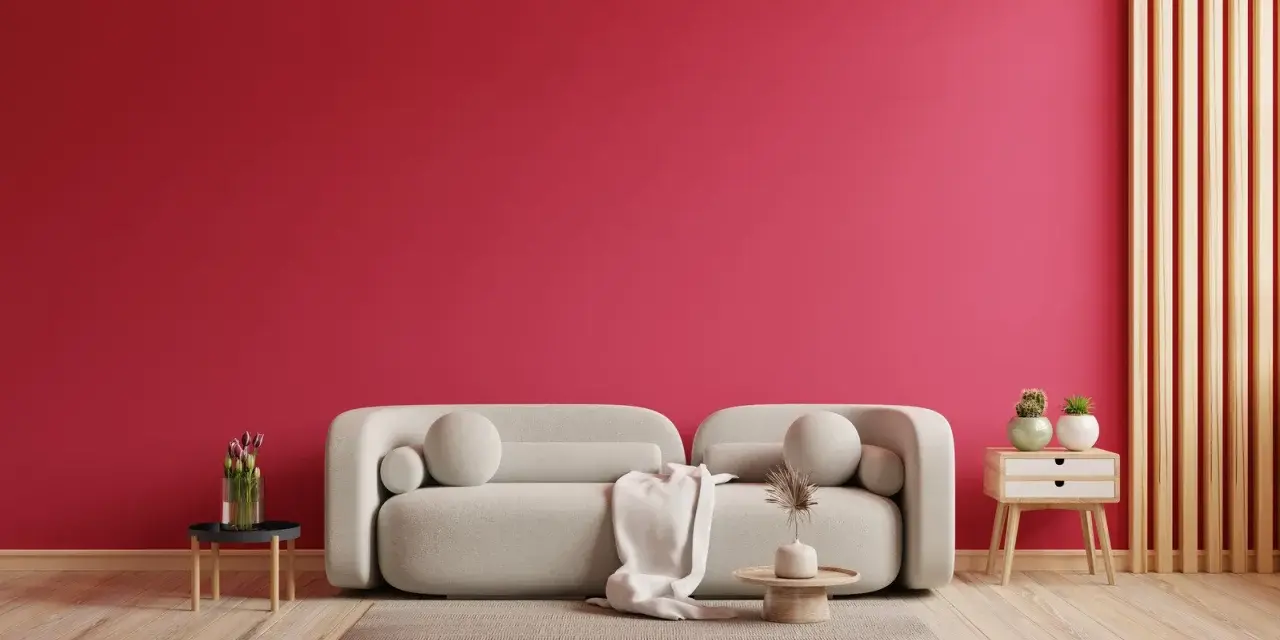 Ściana w kolorze magenta, jak to piękny, żywy kolor, stanowi tło dla jasnej kanapy i drewnianych elementów.