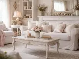 Przytulny salon w stylu shabby chic. Jasna sofa, fotele, stolik kawowy i dekoracje tworzą romantyczną atmosferę.