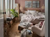 Przytulna sypialnia inspiracje: łóżko z różową pościelą, wiklinowe lampy, dużo roślin i miękkie koce tworzą ciepłą atmosferę.