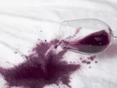 Rozlane czerwone wino na białym materiale. Dowiedz się, jak usunąć plamę z wina, zanim zaschnie.