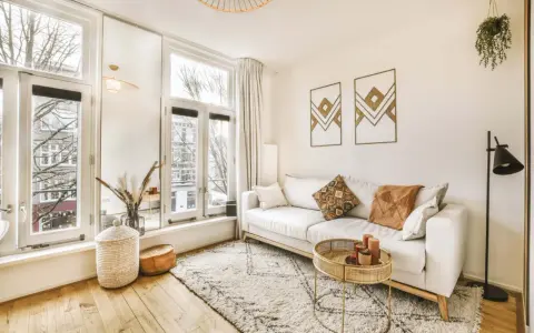 Jasny salon w stylu skandynawskim z wygodną sofą, dywanem i naturalnymi dodatkami.