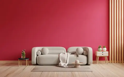 Ściana w kolorze magenta, jak to piękny, żywy kolor, stanowi tło dla jasnej kanapy i drewnianych elementów.