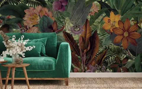 Aksamitna sofa w odcieniach zieleni, obok niej drewniane stoliki z bukietem. W tle bujna, tropikalna tapeta z kwiatami i liśćmi.