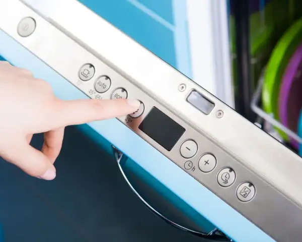Dłoń naciska przycisk "eco" na panelu zmywarki Electrolux, przygotowując ją do ekologicznego cyklu czyszczenia.