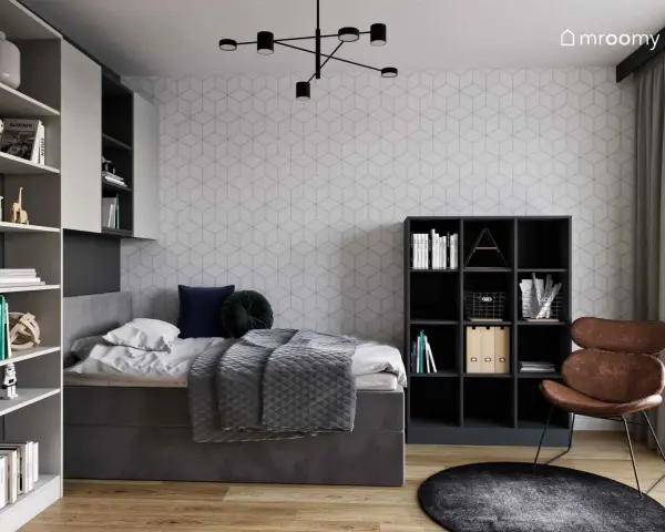 Nowoczesny pokój młodzieżowy dla dziewczyny: inspiracje. Szara tapeta w geometryczne wzory, wygodne łóżko, regały z książkami i stylowy fotel.