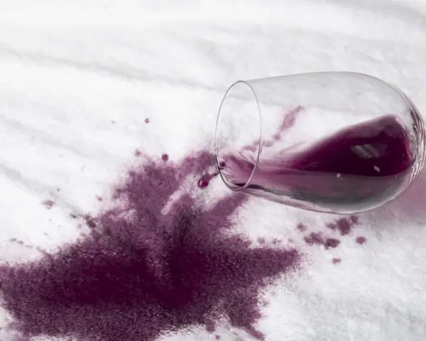 Rozlane czerwone wino na białym materiale. Dowiedz się, jak usunąć plamę z wina, zanim zaschnie.