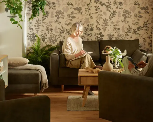 Przytulny salon, gdzie starsza pani pisze w notatniku, a pan czyta na tablecie. Idealne miejsce, by pomyśleć, jak urządzić pokój dla babci.
