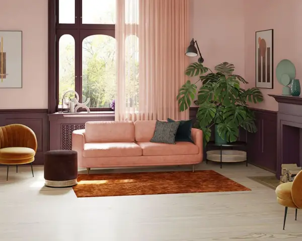 Przytulny salon z kanapą w kolorze pudrowy róż, aksamitnym fotelem i dużą rośliną.