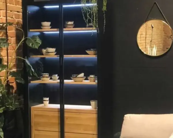 Elegancka witryna w salonie z podświetlanymi półkami, na których stoją misy i filiżanki. Idealna inspiracja, co wstawić do witryny w salonie.