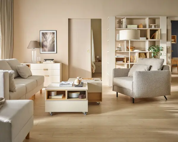 Nowoczesny salon z beżową kanapą, fotelem, stolikiem kawowym i regałem.