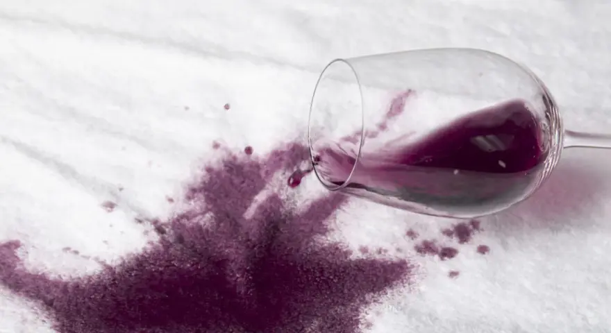 Rozlane czerwone wino na białym materiale. Dowiedz się, jak usunąć plamę z wina, zanim zaschnie.
