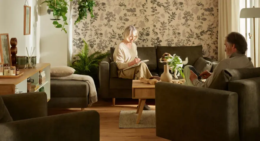 Przytulny salon, gdzie starsza pani pisze w notatniku, a pan czyta na tablecie. Idealne miejsce, by pomyśleć, jak urządzić pokój dla babci.
