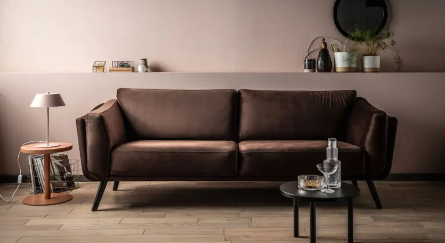 Elegancki brązowy narożnik w salonie, idealnie komponuje się z pastelowymi ścianami i drewnianą podłogą.