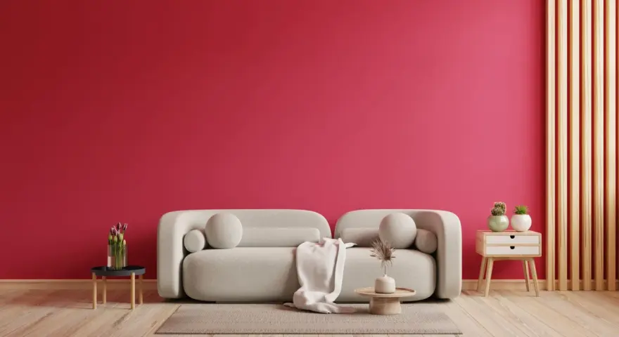 Ściana w kolorze magenta, jak to piękny, żywy kolor, stanowi tło dla jasnej kanapy i drewnianych elementów.