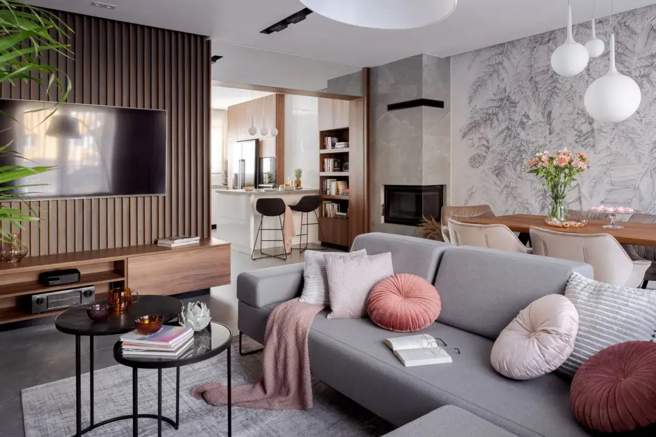 Przytulny salon w stylu modern farmhouse z szarą sofą, kominkiem i otwartą kuchnią.