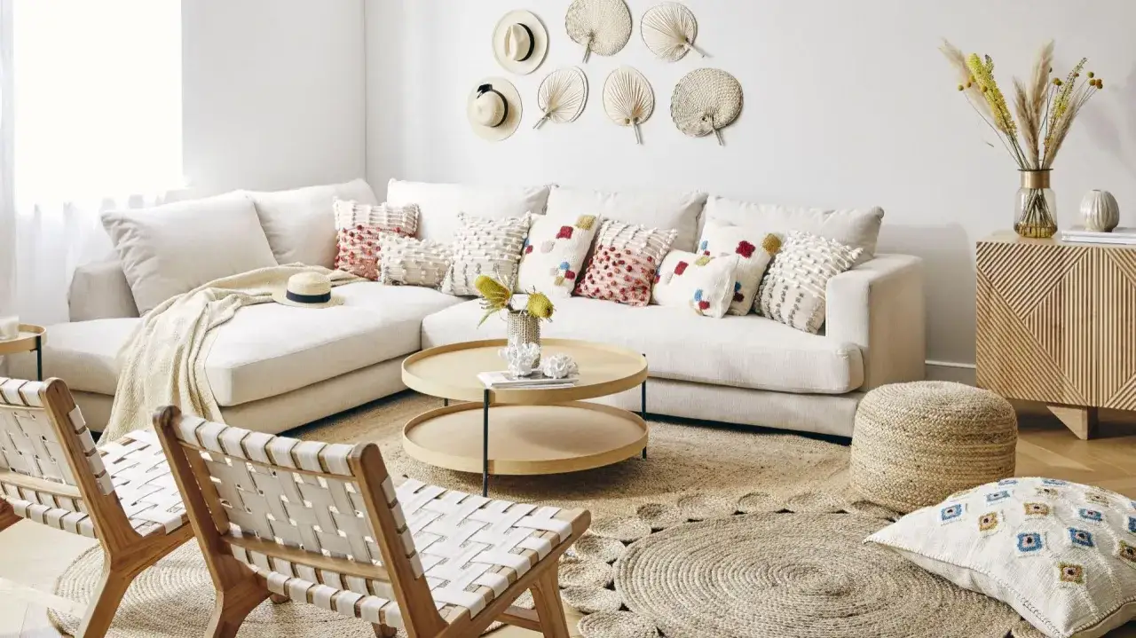 Przytulny salon w stylu scandi boho z beżową sofą, kolorowymi poduszkami, drewnianymi meblami i plecionymi dodatkami.