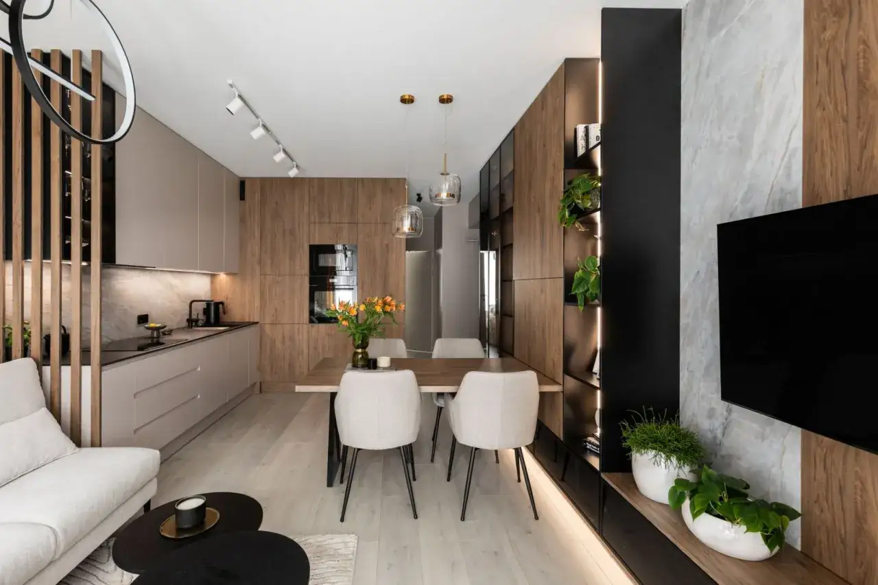 Nowoczesny salon z kuchnią i jadalnią 40m2. Drewniane akcenty, jasne meble i rośliny tworzą przytulną atmosferę.