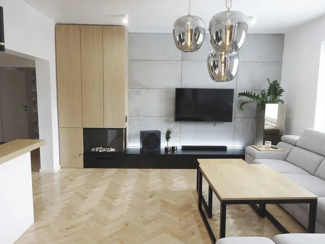Nowoczesna zabudowa ściany w salonie z drewnianymi frontami, betonem architektonicznym i kominkiem.