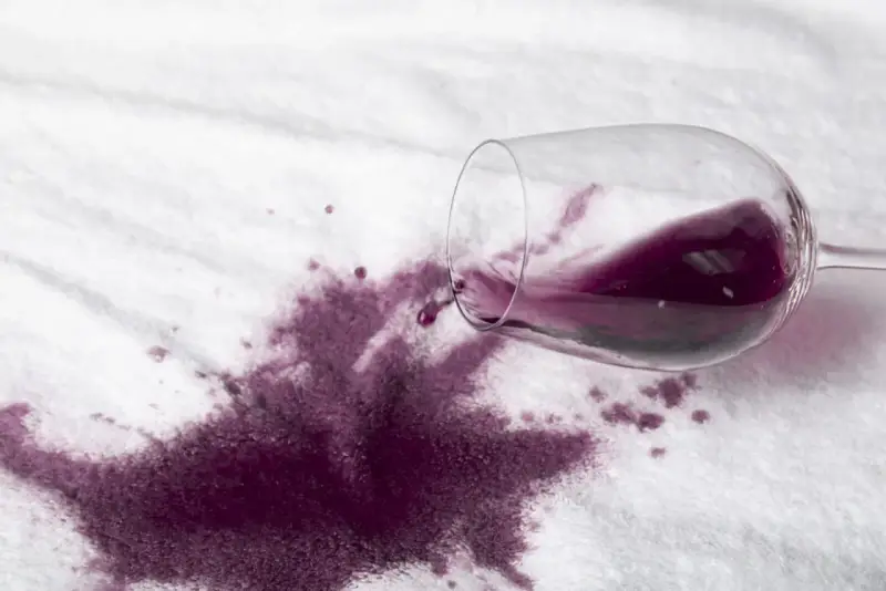 Rozlane czerwone wino na białym materiale. Dowiedz się, jak usunąć plamę z wina, zanim zaschnie.